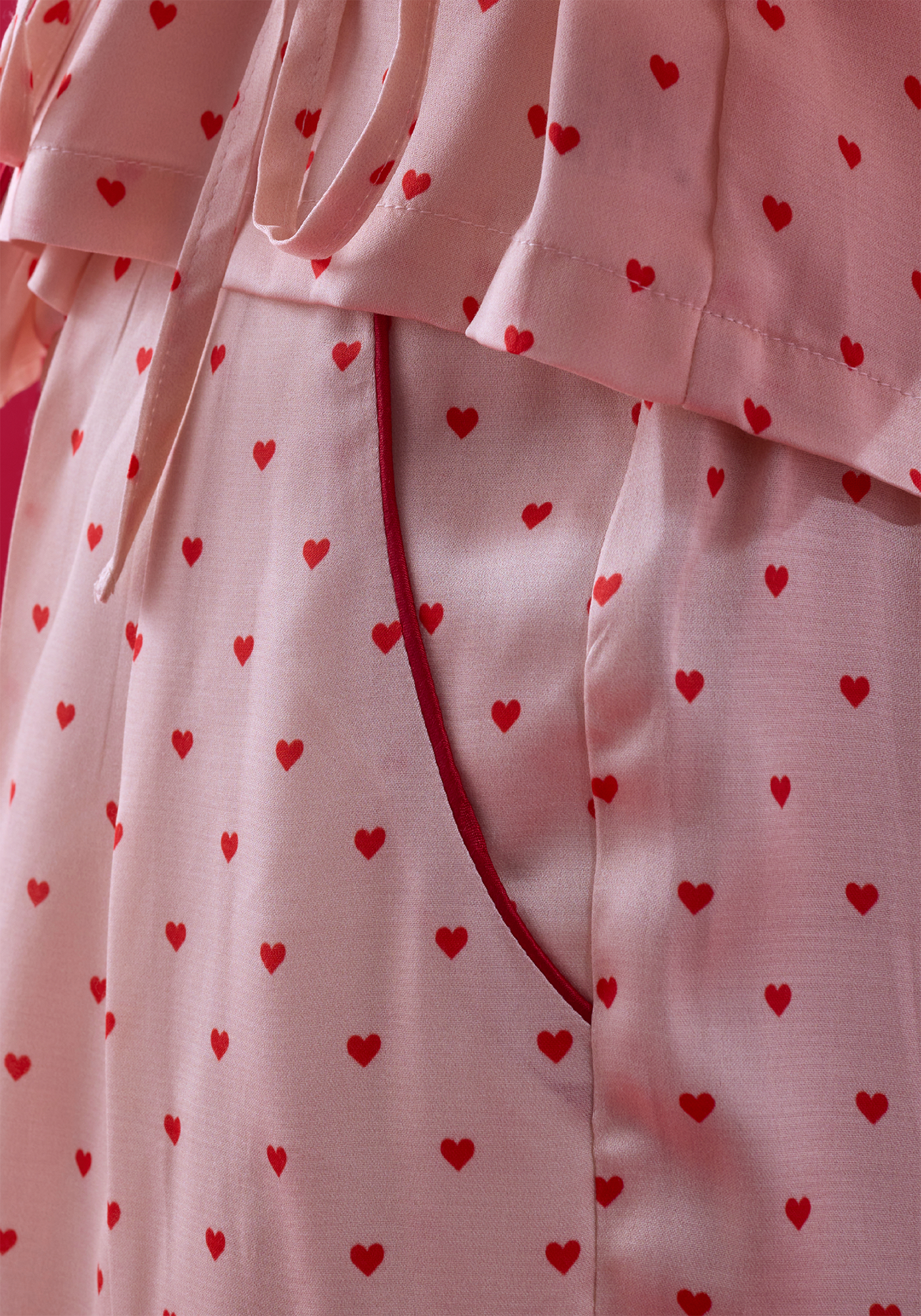 Close-up of satin fabric featuring mini red hearts on a vintage cream base colour.