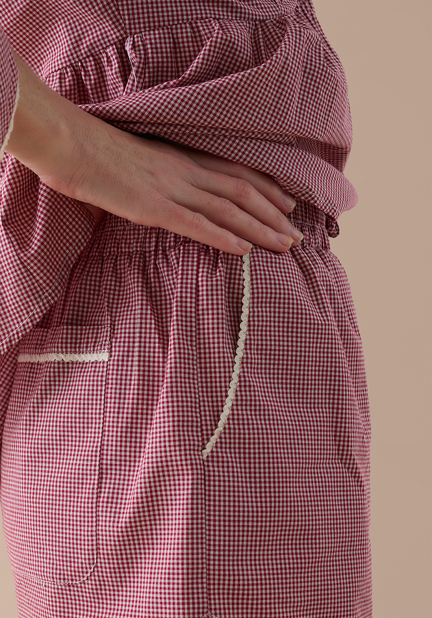 Close-up of cherry gingham PJ sorts with cotton lace trim on a beige background