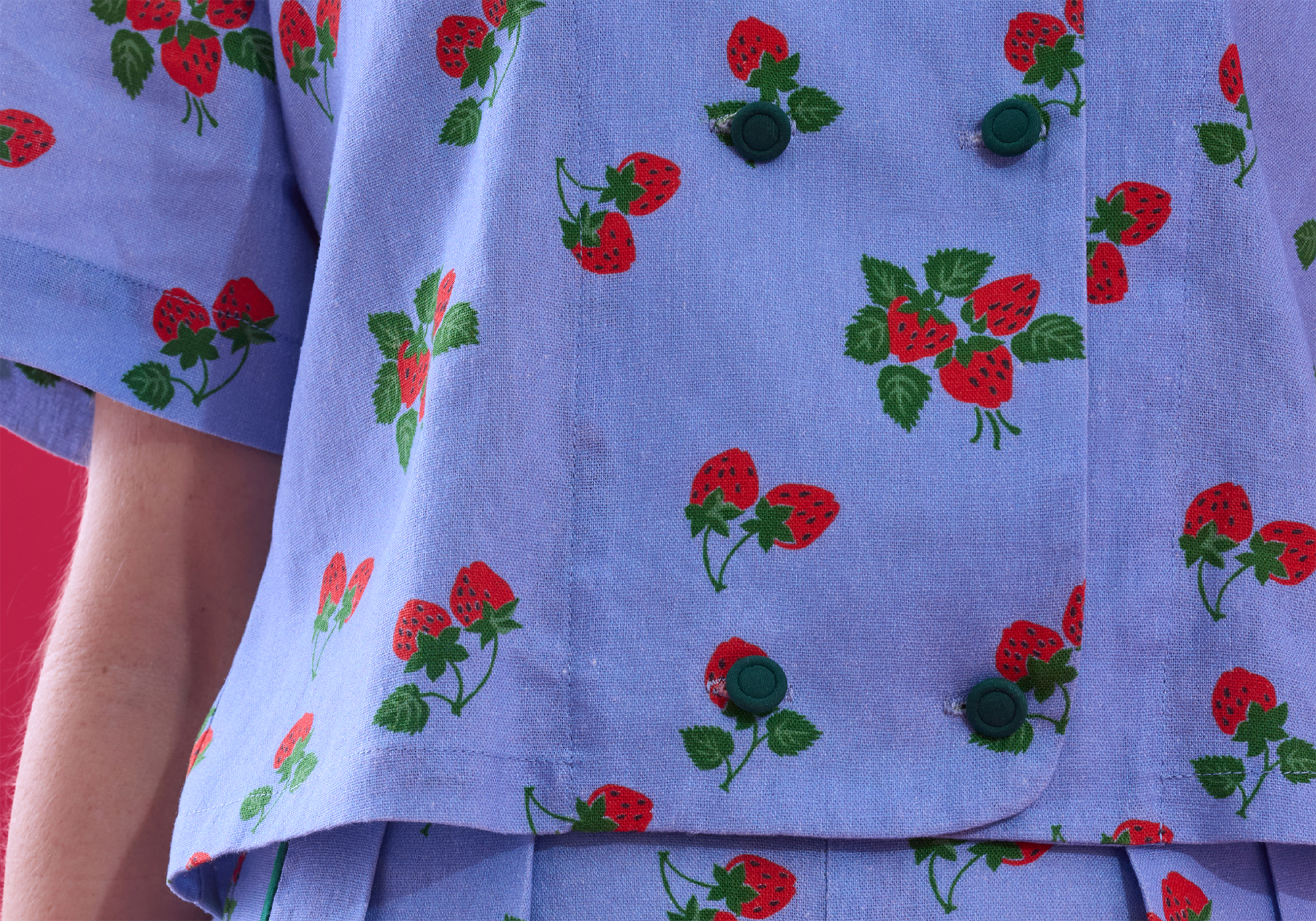 Close-up of a blue fabric with red strawberries with green foliage pattern