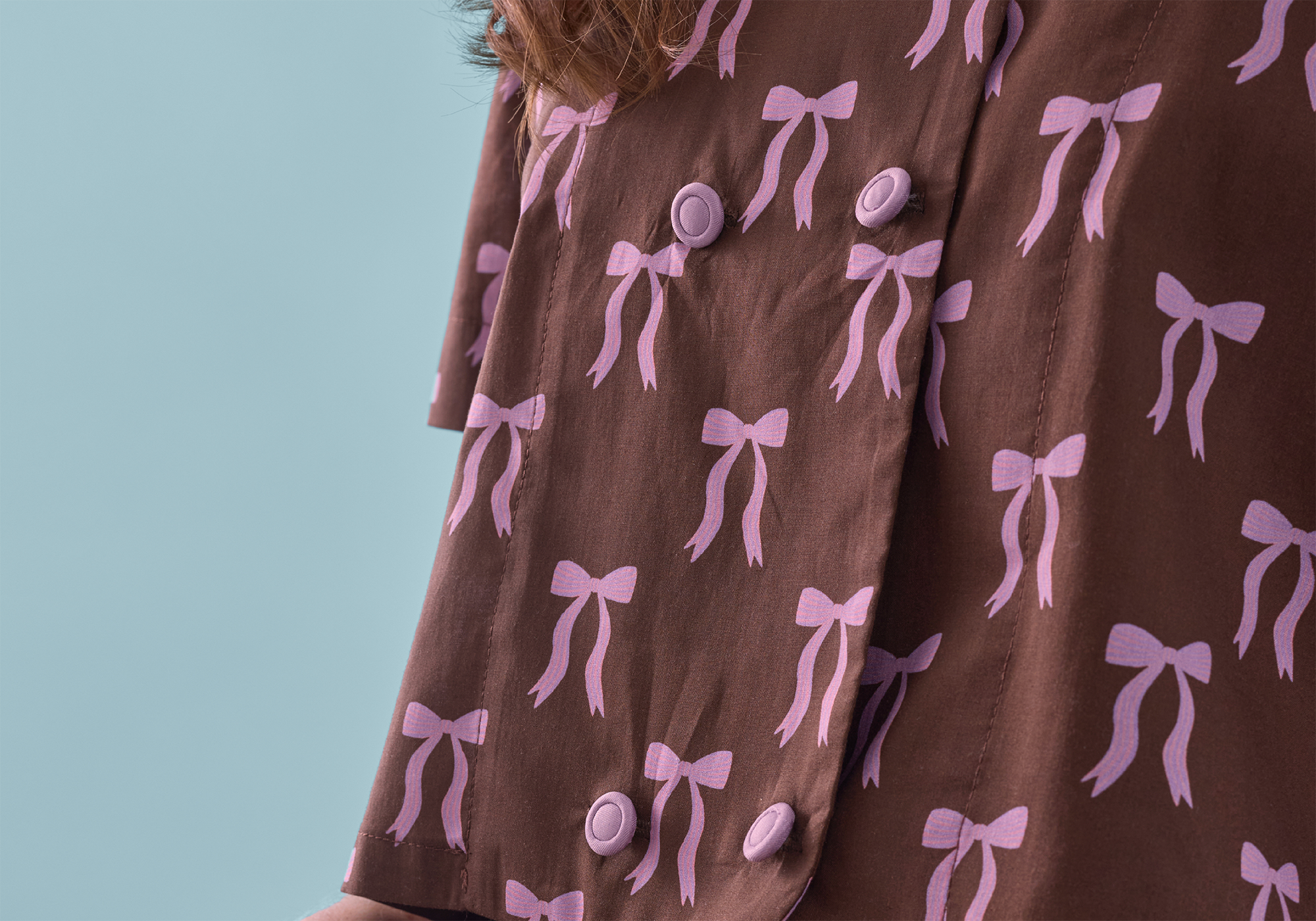Brown dress with pink bow pattern on a light blue background